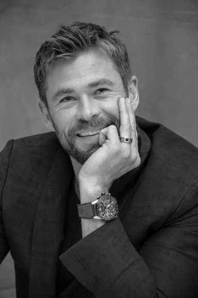 A young female courier smiling while managing packages with a tablet in a warehouse environment.