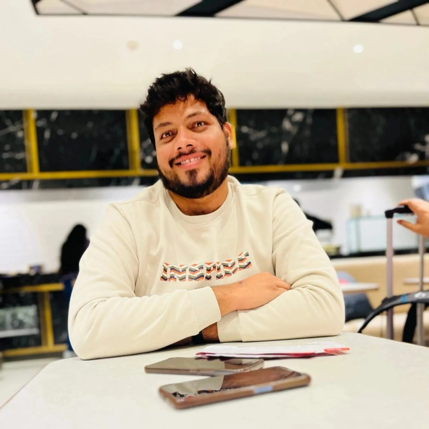 Family wearing traditional Indian clothing enjoys relaxation time on sofa with vibrant tapestry background.