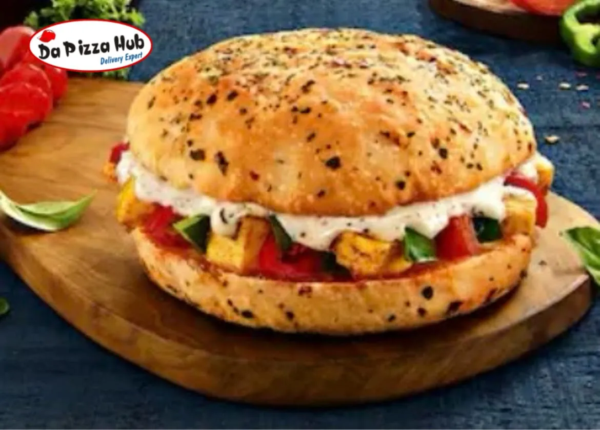 Colorful buffet table featuring mini burgers, pizza, and flowers at an outdoor event.