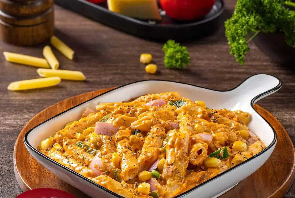 Top view of fast food spread with pizza, burgers, chips, and soda on a table.
